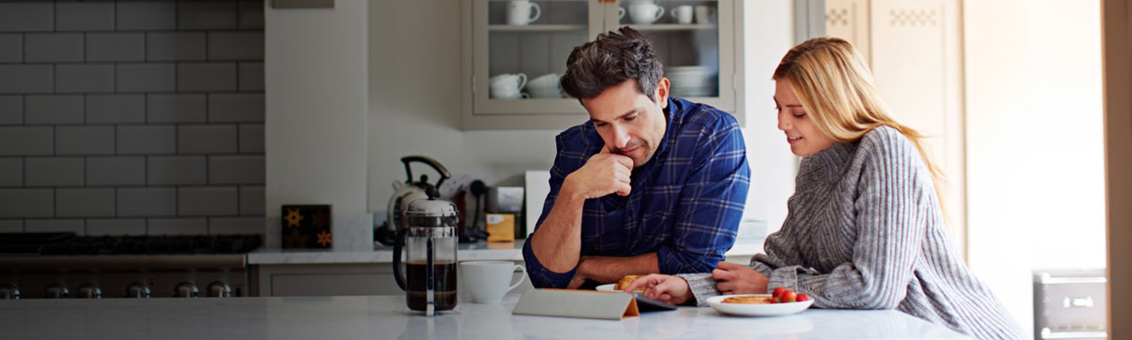 Man and Woman Looking At An iPad In the Kitchen