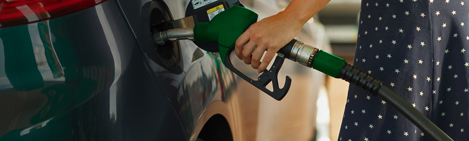 lady pumping gas in a blue dress