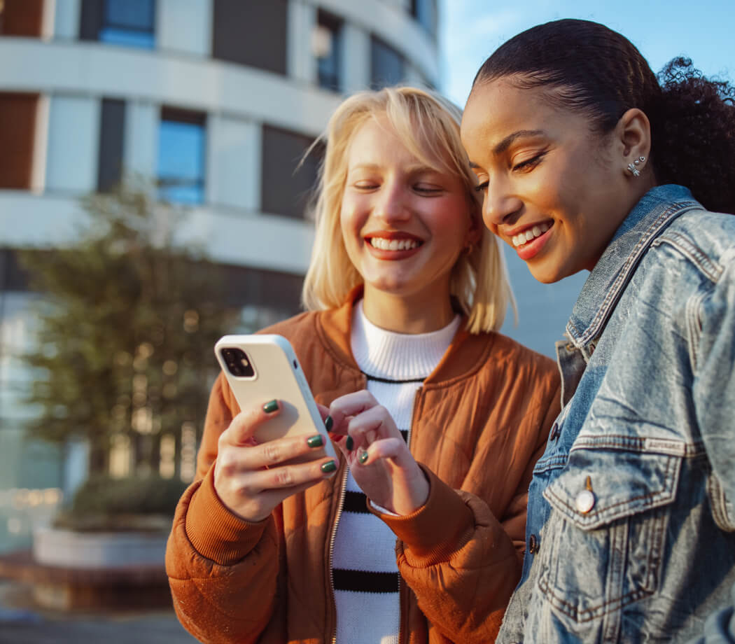 Two young friends look at a mobile phone