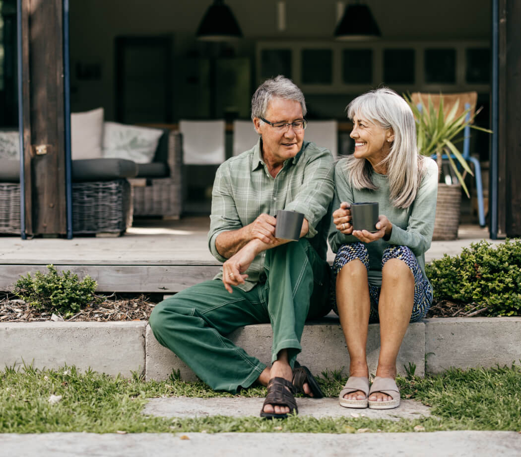 Mature couple sitting outside their home